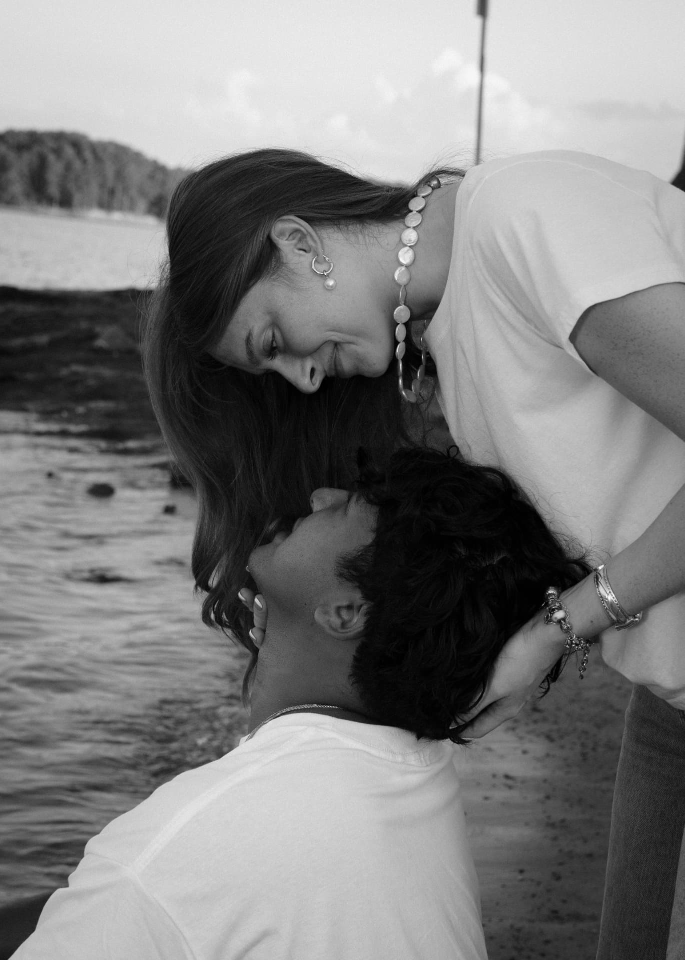 Black and white photograph of a couple sharing a tender moment by the water in North Georgia